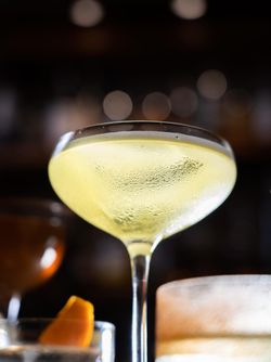Chilled cocktail in a coupe glass with condensation, set against a dimly lit bar background at Junoon restaurant.