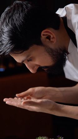 Chef closely inspecting the presentation of a dish in an upscale Indian restaurant kitchen.