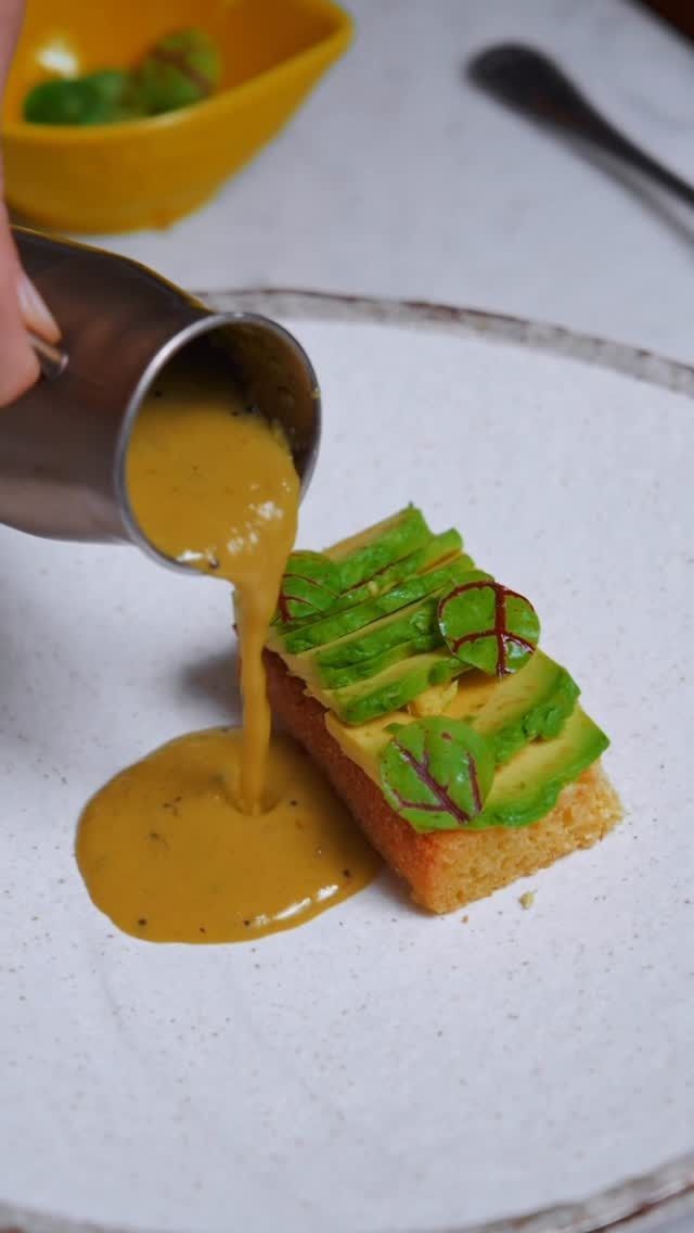 Sauce being poured on a garnished appetizer at Junoon, an upscale Indian restaurant known for fine dining in New York.