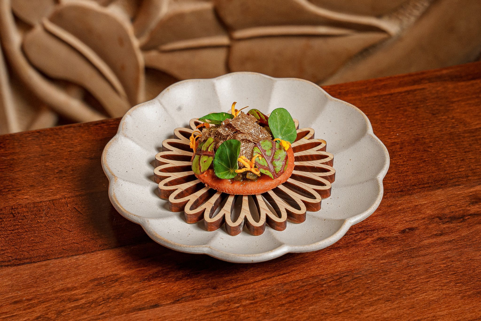 A single fine dining Indian appetizer garnished with microgreens and truffle on artistic ceramic plates at Junoon.