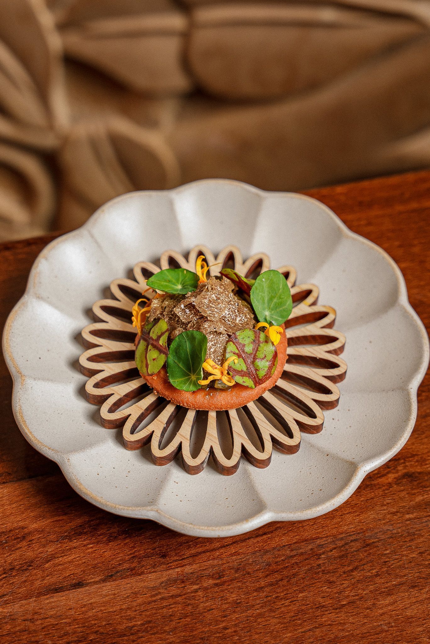 Fine dining Indian restaurant dish featuring garnished appetizer with edible leaves and truffle on decorative plates.